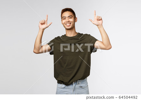 Portrait of proud happy, smiling asian young man, teen guy pointing fingers up and grinning at camera satisfied, person showing way to promo, advertise product or company banner Portrait of proud happy, smiling asian young man, teen guy pointing fingers up and grinning at camera satisfied, person showing way to promo, advertise product or company banner 64504492