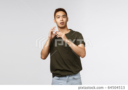 Portrait of startled young asian guy, male student gasping and jumping scared as someone appeared unexpected, raising hands up defense, stare terrified at camera, standing grey background 64504513