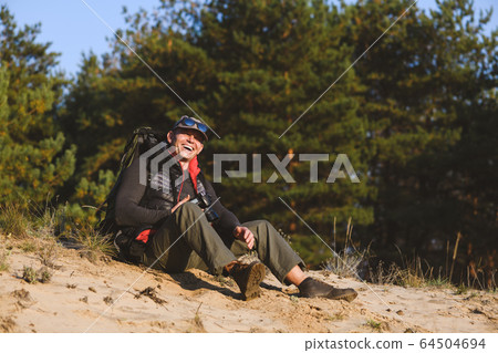 Elderly man with a camera in the forest Elderly man with a camera in the forest 64504694