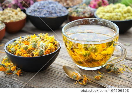 Cup of marigold tea and calendula flowers in bowl. Cup of marigold tea and calendula flowers in bowl. 64506308