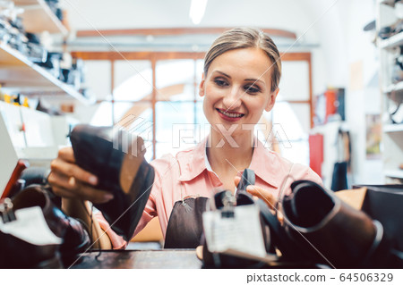 Woman shoemaker taking shoes to be repaired off the shelf Woman shoemaker taking shoes to be repaired off the shelf 64506329