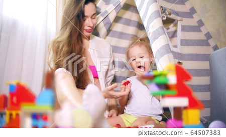 Beautiful pregnant woman and her little baby eat raspberries in toy teepee tent Beautiful pregnant woman and her little baby eat raspberries in toy teepee tent 64507383