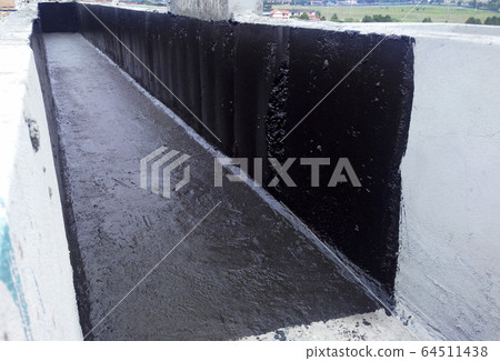 Waterproofing mambrane applied by construction workers on top of concrete slab. Waterproofing layer to prevent water from entering below of the concrete slab. Waterproofing mambrane applied by construction workers on top of concrete slab. Waterproofing layer to prevent water from entering below of the concrete slab. 64511438