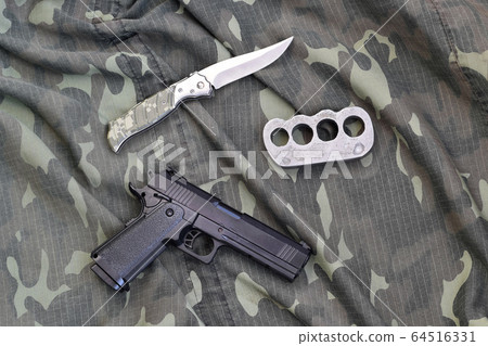 Handgun lies with brass knuckles and knife on Handgun lies with brass knuckles and knife on 64516331