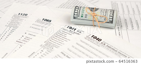 Tax forms lies near roll of hundred dollar bills. Tax forms lies near roll of hundred dollar bills. 64516363