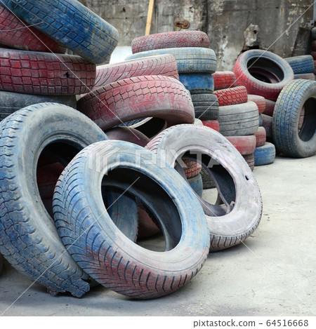 A picture of many old used tires left on a waste A picture of many old used tires left on a waste 64516668