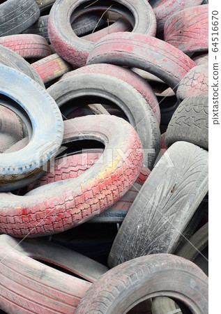 A picture of many old used tires left on a waste A picture of many old used tires left on a waste 64516670