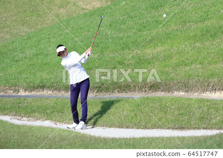 Image of a woman hitting the approach from the rough Image of a woman hitting the approach from the rough 64517747