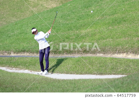 Image of a woman hitting the approach from the rough Image of a woman hitting the approach from the rough 64517759