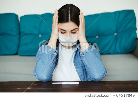 Woman in medical face mask with pregnancy test 64517849