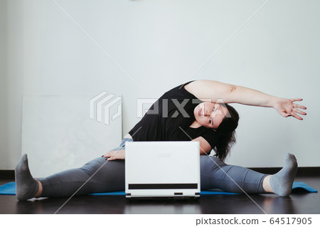 Obese woman doing stretching exercises at home 64517905