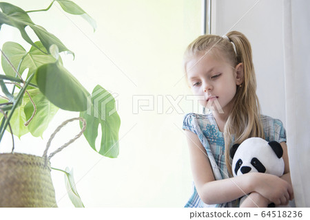 Sad child girl by the window Sad child girl by the window 64518236