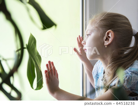 Sad child girl by the window 64518238