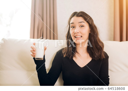 Beautiful young woman with glass of milk at home Beautiful young woman with glass of milk at home 64518608
