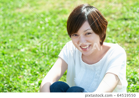 A smiling woman sitting on the meadow 64519550