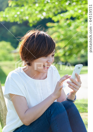 Surprised woman looking at smartphone under the shade 64519551