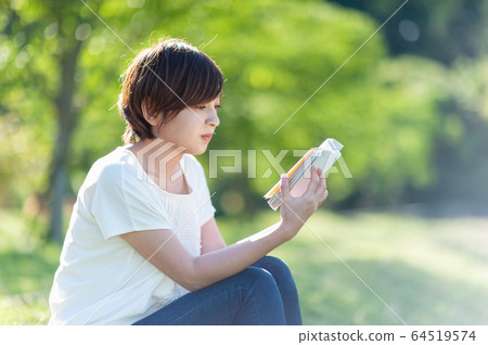 坐在樹蔭下和讀書的婦女 坐在樹蔭下和讀書的婦女 64519574