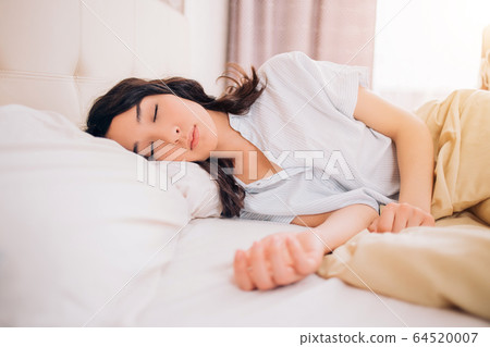 Young beautiful woman sleeping in bed, relaxing in 64520007