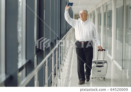 Elegant old man at the airport with a suitcase Elegant old man at the airport with a suitcase 64520009