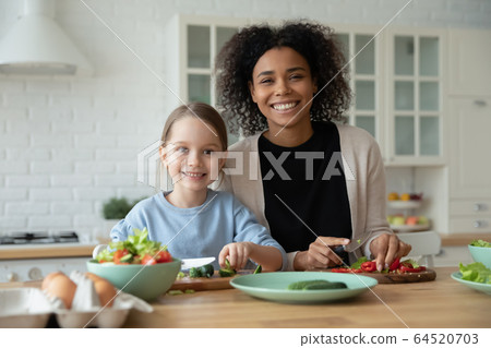 Portrait of multiracial mom and daughter cooking together 64520703