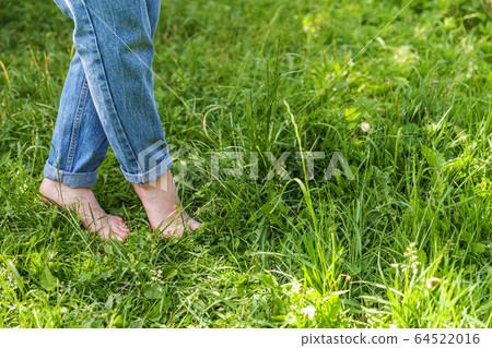Two beautiful female feet walking on grass in Two beautiful female feet walking on grass in 64522016