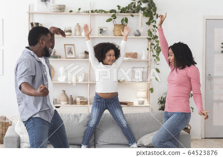 Joyful black family of three dancing dancing together at home 64523876