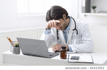 Exhausted doctor napping at workplace, need break in hard pandemic work Exhausted doctor napping at workplace, need break in hard pandemic work 64523932