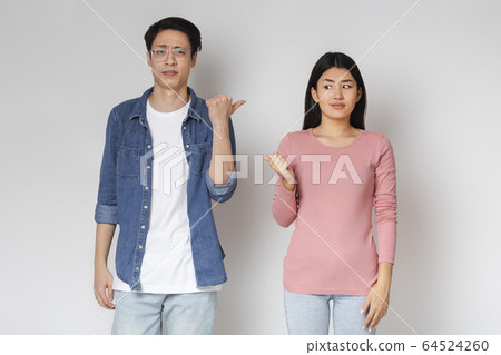 Annoyed asian man and woman pointing at each other 64524260