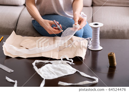 Deficit of protective masks. Woman makes mask 64524476