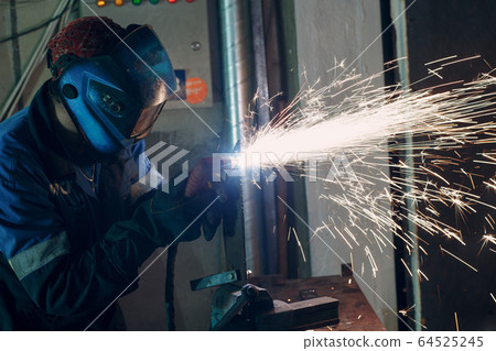 Man in mask cuts metal with plasma cutter. Helmet and spakrs. 64525245