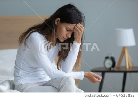 Unhappy woman sitting on bed, feeling depressed, thinking about problems 64525852