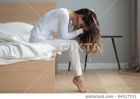 Unhappy woman sitting on bed, feeling depressed, holding head 64527551