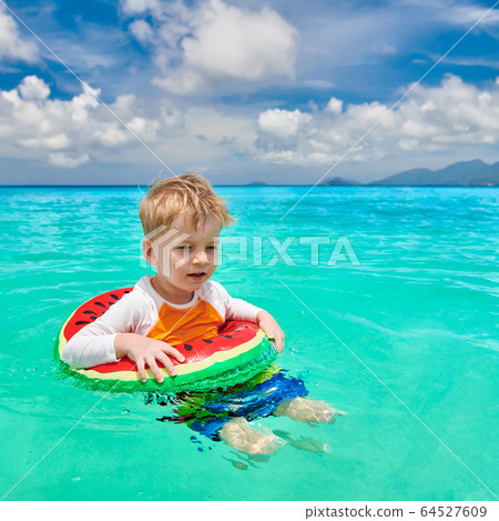 Toddler boy on beach swimming with inflatable ring Toddler boy on beach swimming with inflatable ring 64527609