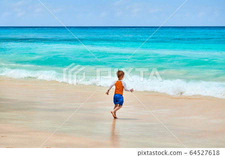 Three year old toddler boy running on beach 64527618