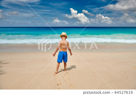 Three year old toddler boy walking on beach 64527619