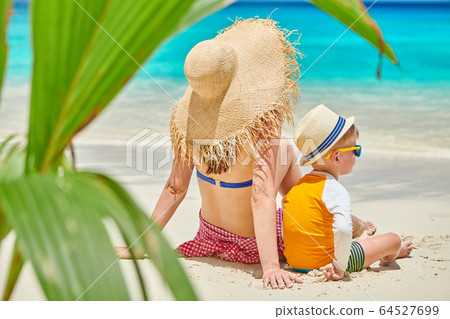 Toddler boy on beach with mother Toddler boy on beach with mother 64527699