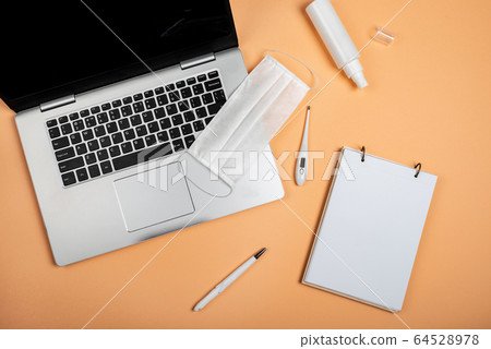 Laptop, notebook, pen, surgical mask, medical gloves, hand sanitizer and digital thermometer on the orange background. Online work or education. 64528978