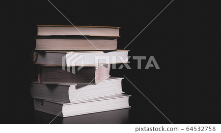 High messy stack of books on a black background with space for text message. High messy stack of books on a black background with space for text message. 64532758