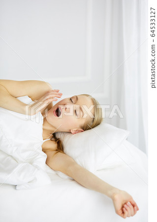 Smiling woman stretching hands in bed after waking up, entering a day happy and relaxed after good night sleep. Sweet dreams, fairy morning concept 64533127