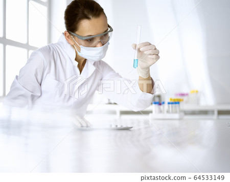 Female laboratory assistant analyzing test tube with blue liquid. Medicine, health care and researching concept 64533149