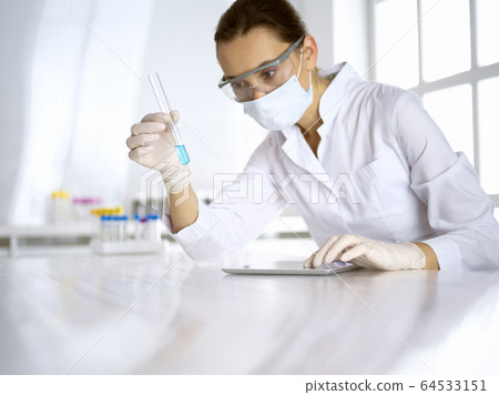 Female laboratory assistant analyzing test tube with blue liquid. Medicine, health care and researching concept 64533151