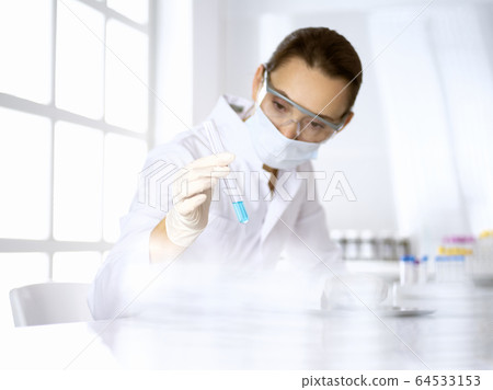 Female laboratory assistant analyzing test tube with blue liquid. Medicine, health care and researching concept Female laboratory assistant analyzing test tube with blue liquid. Medicine, health care and researching concept 64533153