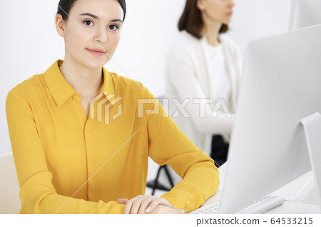 Businesswoman in mustard colored blouse looking at camera at office, headshot Businesswoman in mustard colored blouse looking at camera at office, headshot 64533215