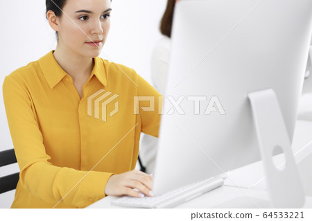 Businesswoman in mustard colored blouse looking at camera at office, headshot Businesswoman in mustard colored blouse looking at camera at office, headshot 64533221