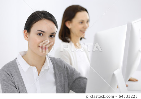 Business woman looking at camera at the background of working colleagues. Office life concept, headshot Business woman looking at camera at the background of working colleagues. Office life concept, headshot 64533223