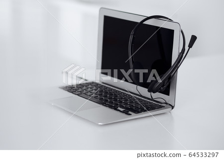 Call center and communication support, customer service help desk. VOIP headset on laptop computer 64533297