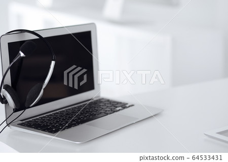 Call center and communication support, customer service help desk. VOIP headset on laptop computer Call center and communication support, customer service help desk. VOIP headset on laptop computer 64533431
