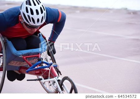 Determined handicapped male athlete in helmet racing in specialized handcycle 64534572