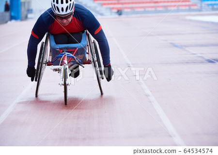 Determined athlete in sportswear and helmet participating in wheelchair race Determined athlete in sportswear and helmet participating in wheelchair race 64534574