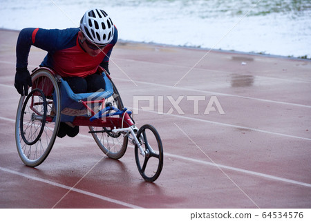 Strong-willed athlete in sportswear and helmet training in racing wheelchair Strong-willed athlete in sportswear and helmet training in racing wheelchair 64534576